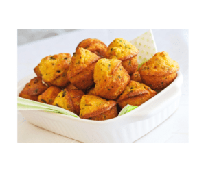 Golden mini cornbread muffins with savory herbs arranged in a white serving dish for catered meals, buffets, and appetizers.