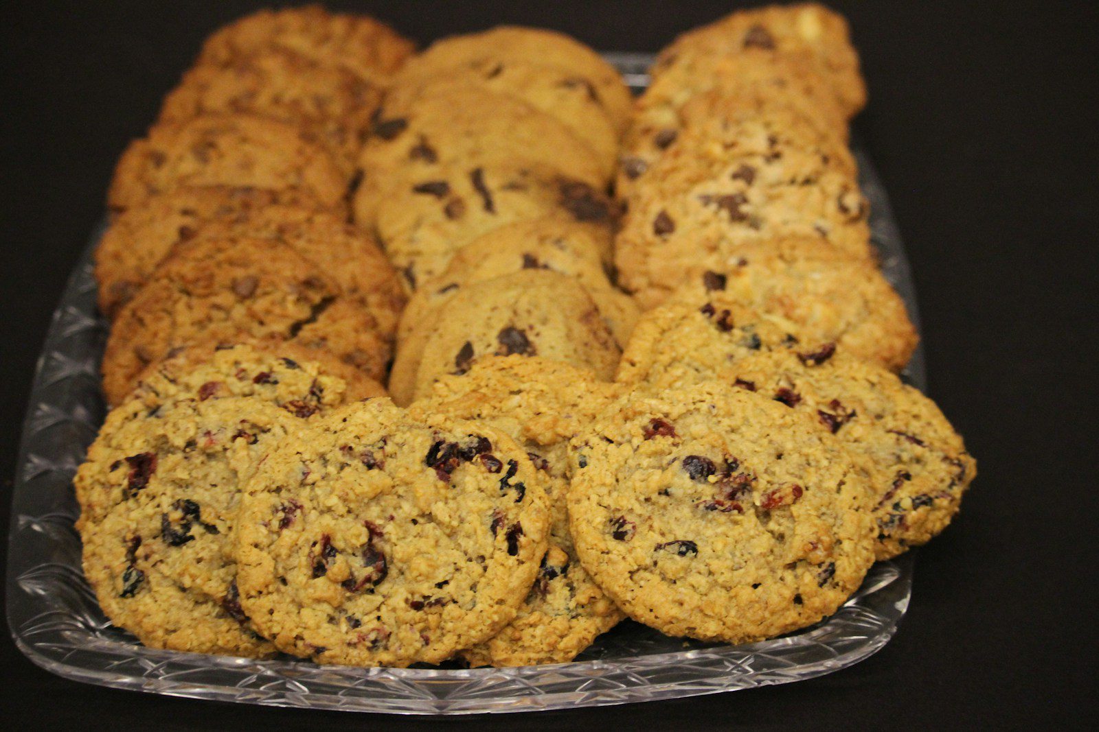 Assorted freshly baked cookies arranged on a serving platter, including oatmeal raisin, chocolate chip, and other homemade cookie varieties.
