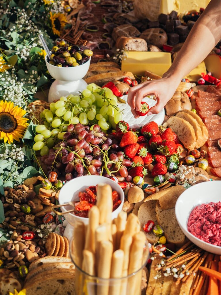 Charleston grazing table with cheeses, cured meats, strawberries, grapes, breads, olives, nuts, dips and fresh flowers.
