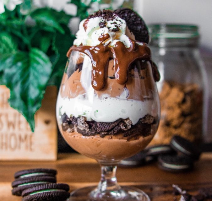 Rich Oreo chocolate mousse parfait layered with chocolate mousse, crushed chocolate sandwich cookies, whipped cream, chocolate drizzle, and cookie crumbles in an elegant dessert glass for catered events in Charleston, SC.