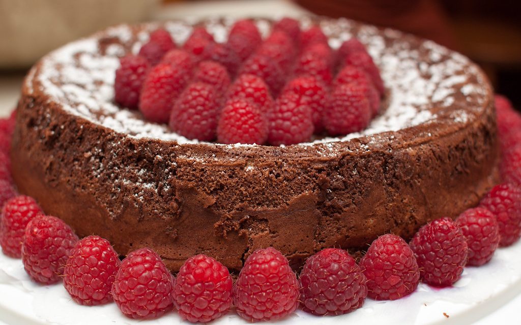 Gluten-free flourless chocolate cake topped with fresh raspberries and powdered sugar, served as a gourmet dessert for weddings, corporate events, and catered celebrations in Charleston, SC.
