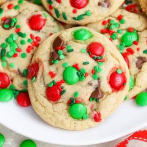Soft Christmas M&M cookies topped with red and green candy-coated chocolates, chocolate chips, and festive sprinkles served on a white plate for holiday dessert catering in Charleston, SC.