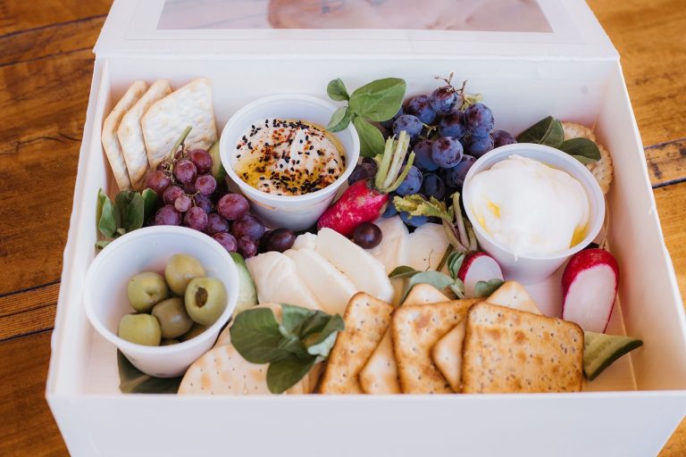 Gourmet charcuterie gift box with artisan cheeses, crackers, grapes, olives, creamy dips, fresh radishes, and seasonal garnishes arranged in an elegant presentation for catering and gifting in Charleston, SC.